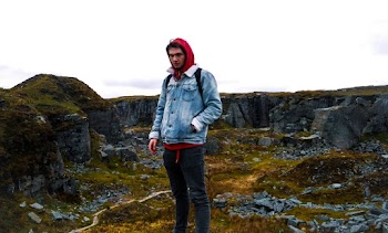 Photo of a man wearing a denim jacket standing on rocky landscape