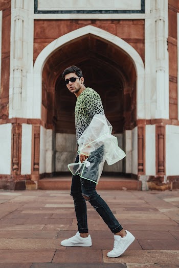 Photo of a Man Wearing a Raincoat Walking Near a Building