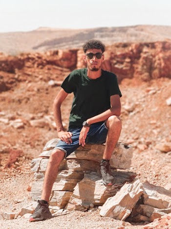 Photo of a Man Wearing Black Crew-neck T-shirt Sitting on Rocks
