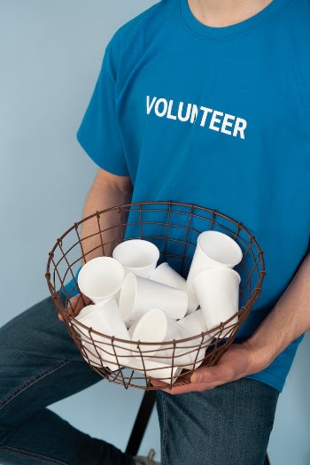 Photo of a Person Holding a Basket with Paper Cups