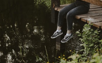 Photo of a Person Sitting on Wood Near Body of Water