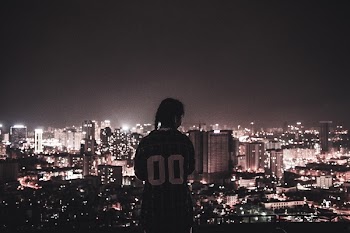 Photo of a Person Watching over City Lights during Night Time
