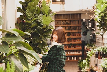 Photo of a Smiling Woman Standing Near Bushes