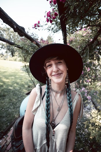 Photo of a smiling Woman wearing a grey v-neck sleeveless top and a hat