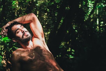Photo of a Topless Man Surrounded by Plants