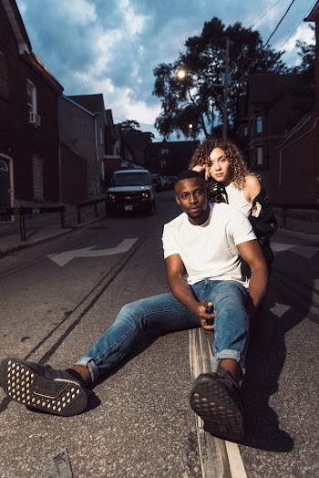 Photo of a Woman Behind a Man Who Is Sitting on Road