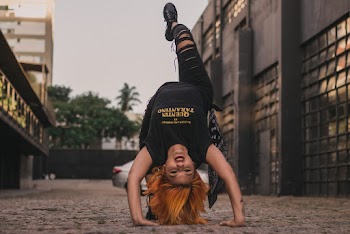 Photo of a Woman Doing a Back Flip on Concrete Floor Near Buildings
