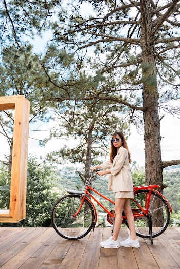 Photo of a Woman Holding a Bike's Handlebars on a Wooden Floor