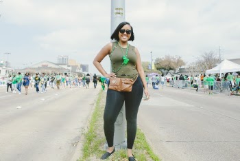Photo of a Woman in Green Sleeveless Top and Black Leggings Standing by Metal Pole