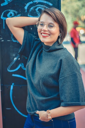 Photo of a Woman in Grey Top Posing Near Wall