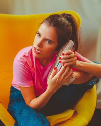 Photo of a Woman in Pink T-shirt Sitting on a Yellow Chair