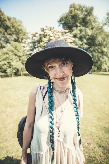 Photo of a woman in white sleeveless top and gray fedora hat