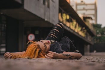 Photo of a Woman Lying on Her Back  Near a Building
