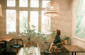 Photo of a Woman Sitting Beside Window