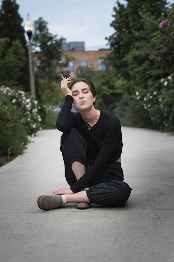 Photo of a woman sitting on gray floor smoking cigarette