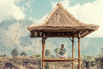 Photo of a Woman Sitting under a Thatch Roof  Gazebo 