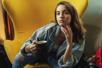 Photo of a Woman Sitting While Holding a Black Ceramic Mug