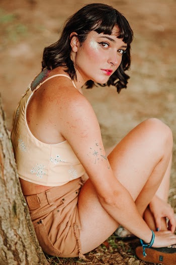 Photo of a Woman Sitting While Leaning on a Tree