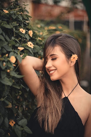Photo of a woman smiling facing a flowering tree