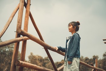 Photo of a Woman Standing Beside Bamboo Post