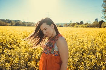 Photo of a Woman Standing by a Flower Field.
