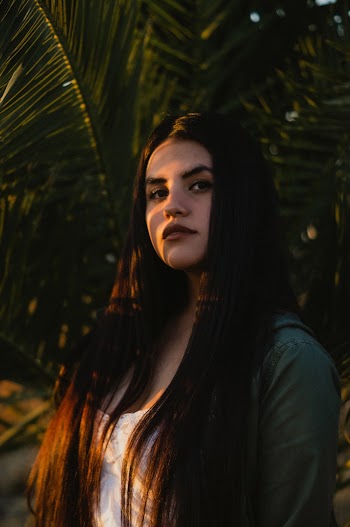 Photo of a Woman Standing Near Green Palm Tree