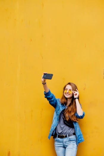 Photo of a Woman Taking a Selfie Near a Yellow Wall · Free Stock Photo