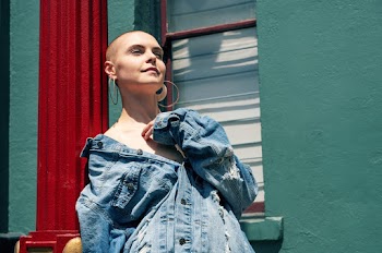 Photo of a woman wearing a blue denim jacket standing near a window