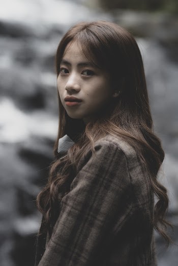 Photo of a woman wearing brown plaid coat looking at the camera