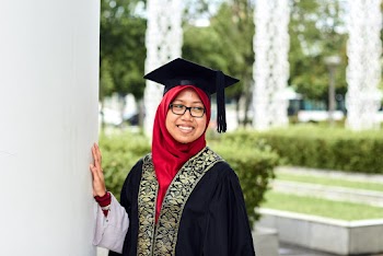 Photo of a Woman Wearing Graduation Gown and Mortar Board