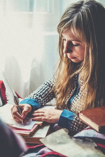 Photo of a Woman Writing on Paper