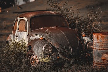 Photo of Abandoned Vintage Volkswagen Beetle Near Rusty Drum