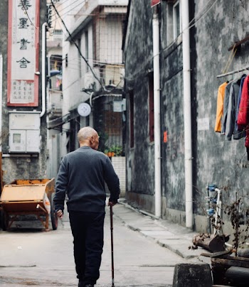Photo of an elderly man walking on an alley