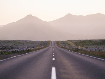 Photo of an Empty Road Near Fog Covered Mountains 