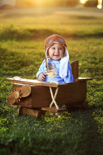 Photo of Baby Sitting on Wooden Airplane