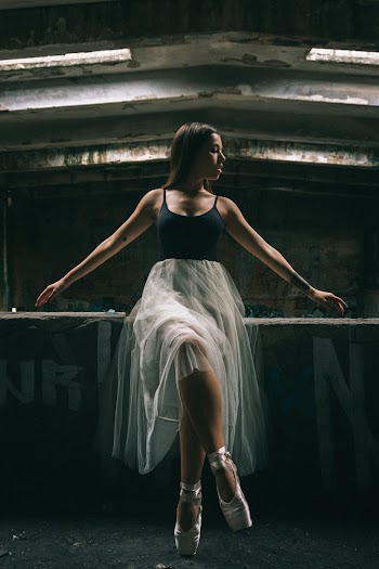 Photo of Ballerina in Black and White Outfit Sitting on Wall