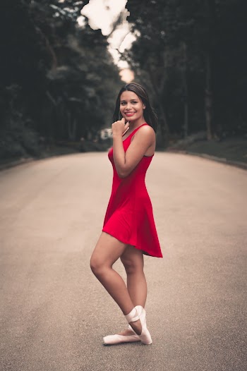 Photo of Ballerina in Red Dress Posing In the Middle of the Road