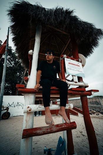 Photo of Barefoot Man in Black T-shirt and Pants Sitting in Lifeguard Tower