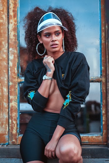 Photo of Beautiful Woman Black Long-sleeved Shirt and Black Shorts Sitting Next to Window Posing