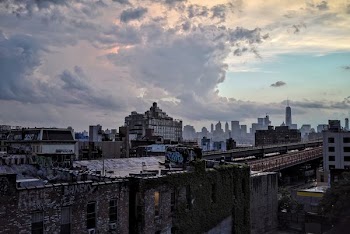 photo of black concrete building under white clouds at noontime