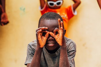 Photo of Boy Doing Hand Sign on His Face