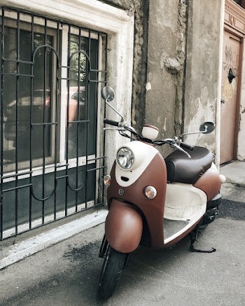 Photo of Brown and White Motor Scooted Parked Near Window