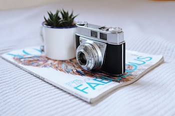 Photo Of Camera On Top Of Magazine
