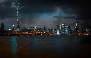 Photo of Chicago Cityscape at Night While Lightning Strikes High Rise Building