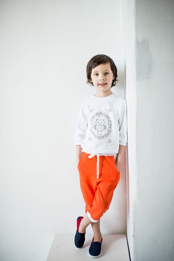 Photo of Child Leaning on Wall With Feet Crossed