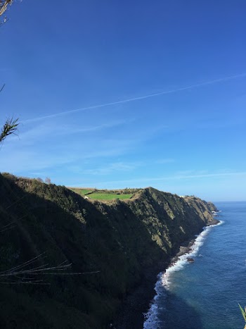 Photo of Cliff Beside a Body of Water Under Blue Sky
