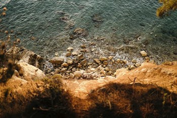 photo of cliff with body of water during daytime