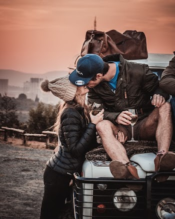 Photo of Couple Kissing While Sitting on Vehicle