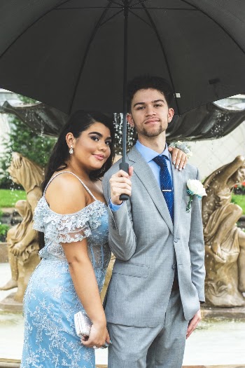 Photo of Couple Standing Under Umbrella Near Water Fountain