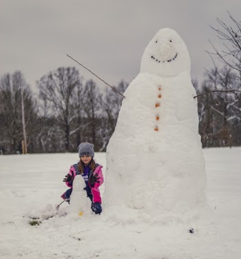 Photo of Girl Beside a Huge Snowman